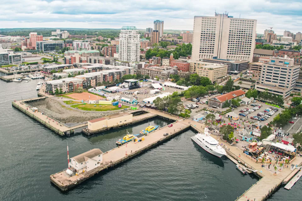 Aerial view of Halifax Waterfront with people milling around on docks among yellow umbrellas and business patios.